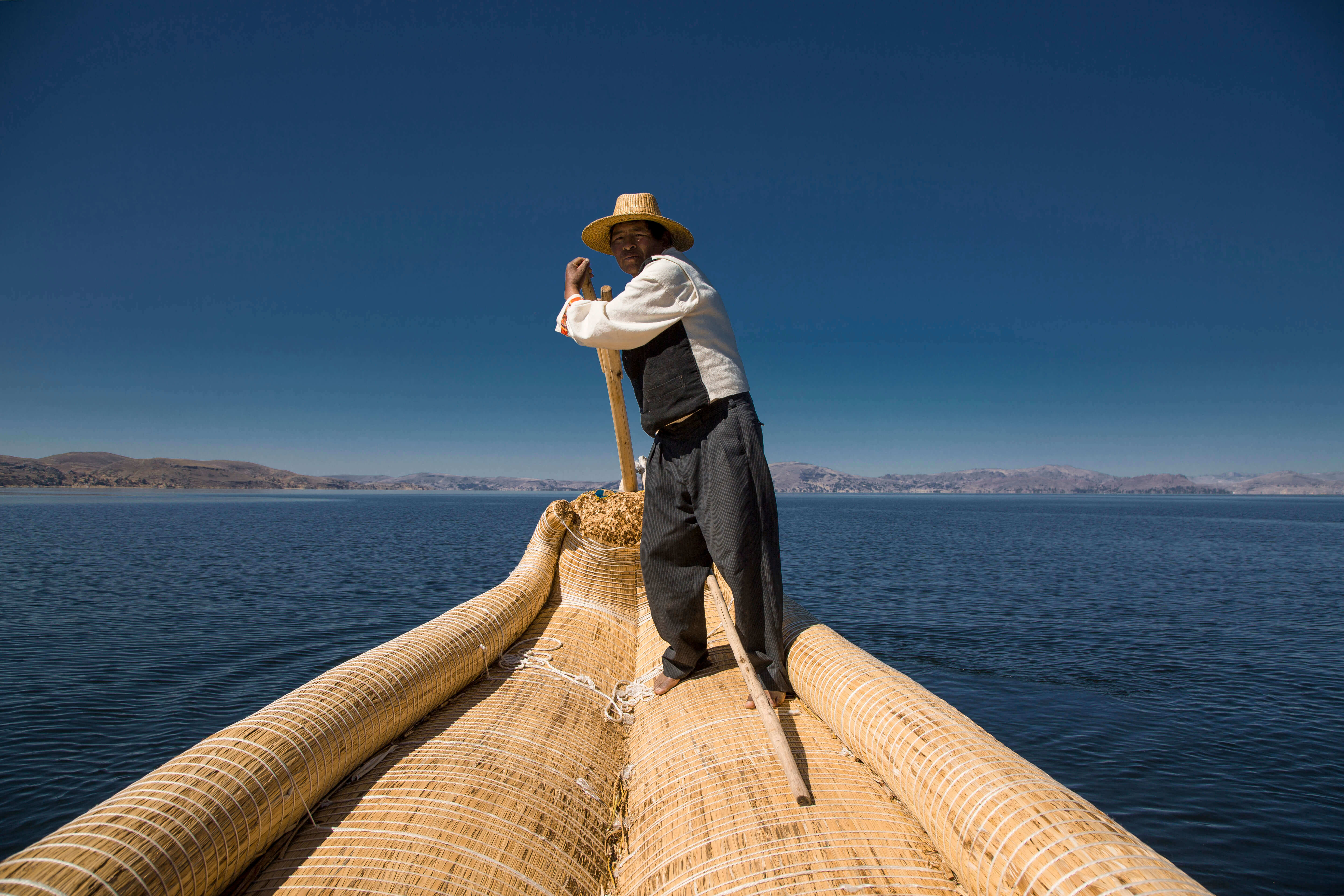Traditional reed boat glides across Peru's Lake Titicaca in the Andean highlands. 