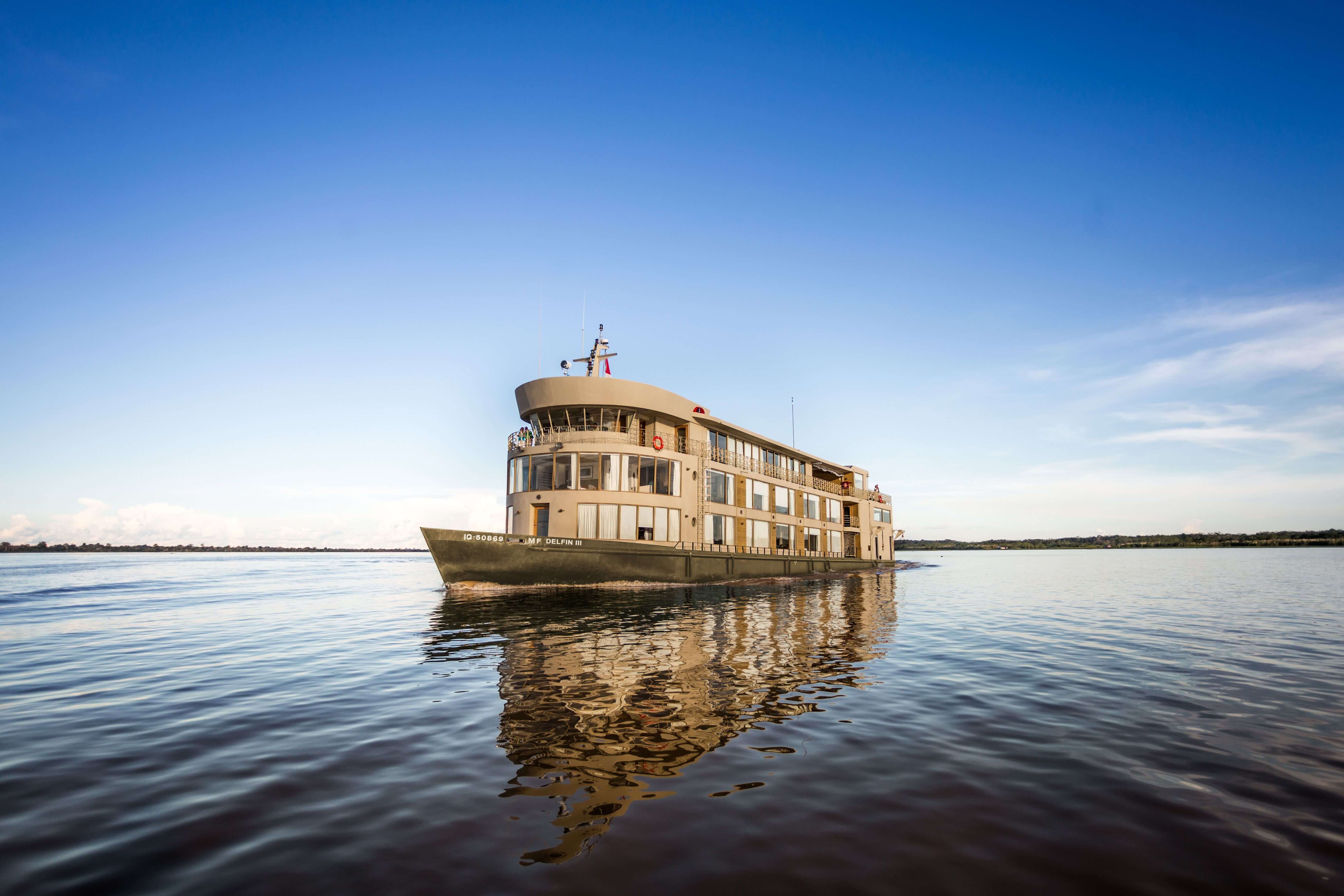 The Delfin III glides over glassy Amazon waters, offering luxury and adventure deep in the jungle. 