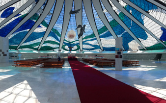 Interior of the Cathedral of Brasilia, showcasing stained glass ceiling and suspended angel sculptures in modernist design. 
