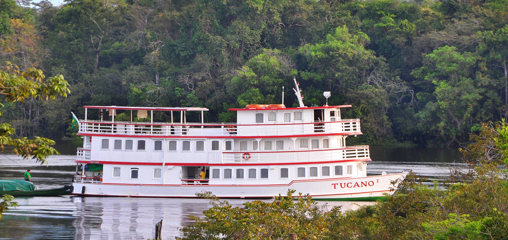 The Tucano Amazon cruise boat on the Rio Negro surrounded by lush rainforest, near Manaus, Brazil. 