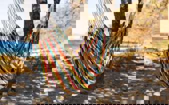 Relaxing in a colourful hammock strung between palm trees on a quiet tropical beach. 