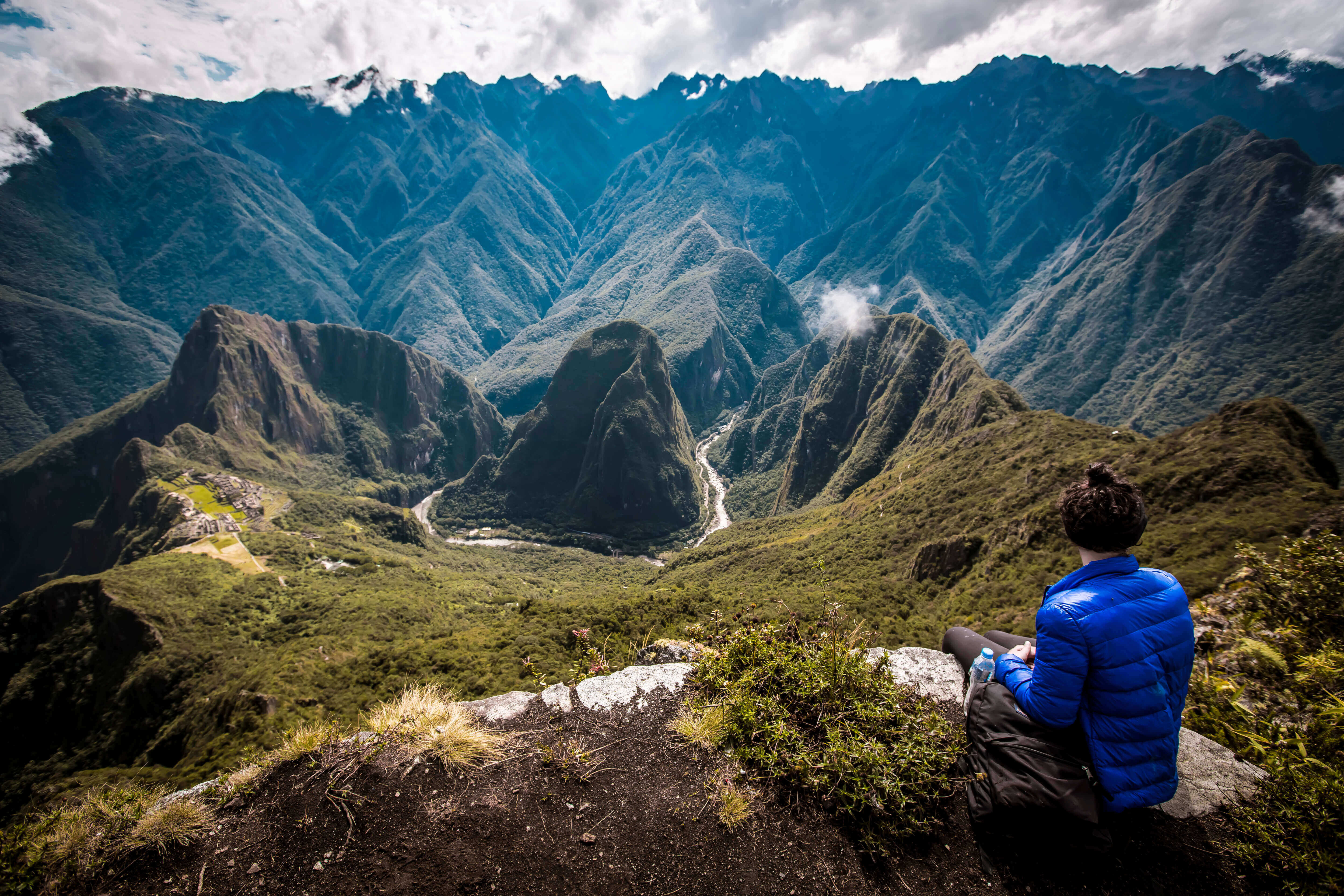 Hiker overlooking the Machu Picchu ruins from a high mountain viewpoint in the Peruvian Andes. 