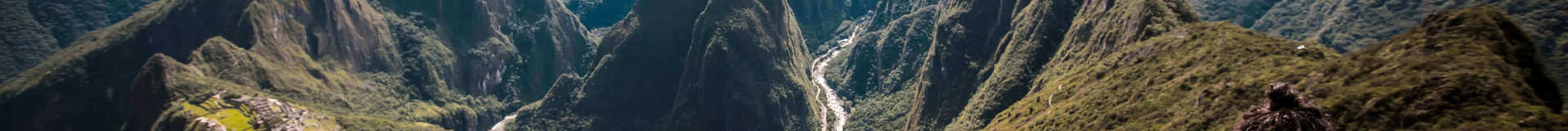 Hiker overlooking the Machu Picchu ruins from a high mountain viewpoint in the Peruvian Andes. 