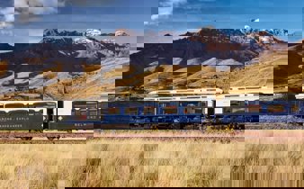 The Belmond Andean Explorer train crossing the high plans of Peru with the Andes in the background. 